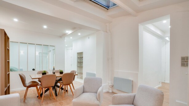 A modern, well-lit room with a dining table, chairs, and a glass coffee table.