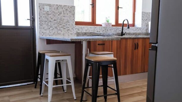Une cuisine avec deux tabourets, un évier et des placards en bois.