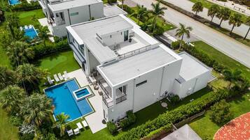 A modern multi-story residential building with a swimming pool and landscaped gardens.