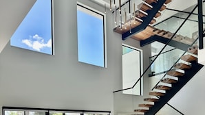A spacious living area with a modern staircase, large windows, and a pool view. - SALT HAUS Top Rated 6BR/6BAContemporary Retreat, Heated Pool/Spa. Walk to Beach! (Juno Beach)