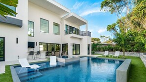 A modern two-story house with a swimming pool, outdoor seating, and a balcony. - SALT HAUS Top Rated 6BR/6BAContemporary Retreat, Heated Pool/Spa. Walk to Beach! (Juno Beach)