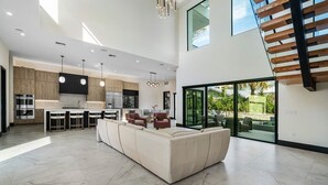 A spacious modern kitchen with high ceilings, a large island, and bar stools. - SALT HAUS Top Rated 6BR/6BAContemporary Retreat, Heated Pool/Spa. Walk to Beach! (Juno Beach)