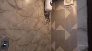 A bathroom with a shower, toilet, and a hand dryer mounted on the wall. - Hotel Rajmahal Palace (Prayagraj)