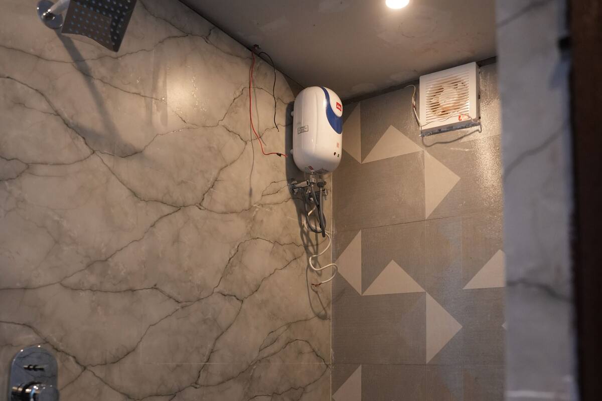 A bathroom with a shower, toilet, and a hand dryer mounted on the wall.