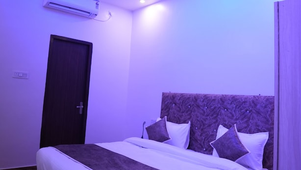 A modern bedroom with a bed, a ceiling fan, and an air conditioning unit. - Hotel Rajmahal Palace (Prayagraj)