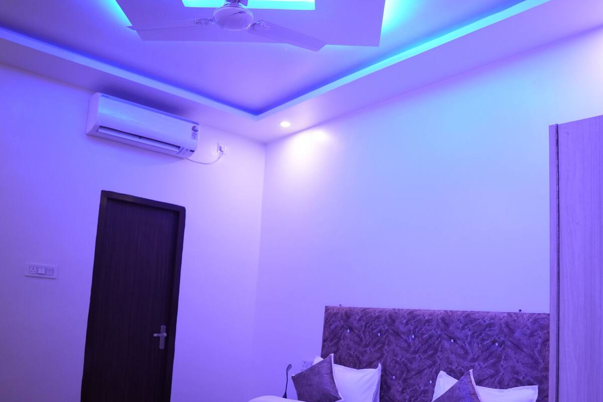 A modern bedroom with a bed, a ceiling fan, and an air conditioning unit.