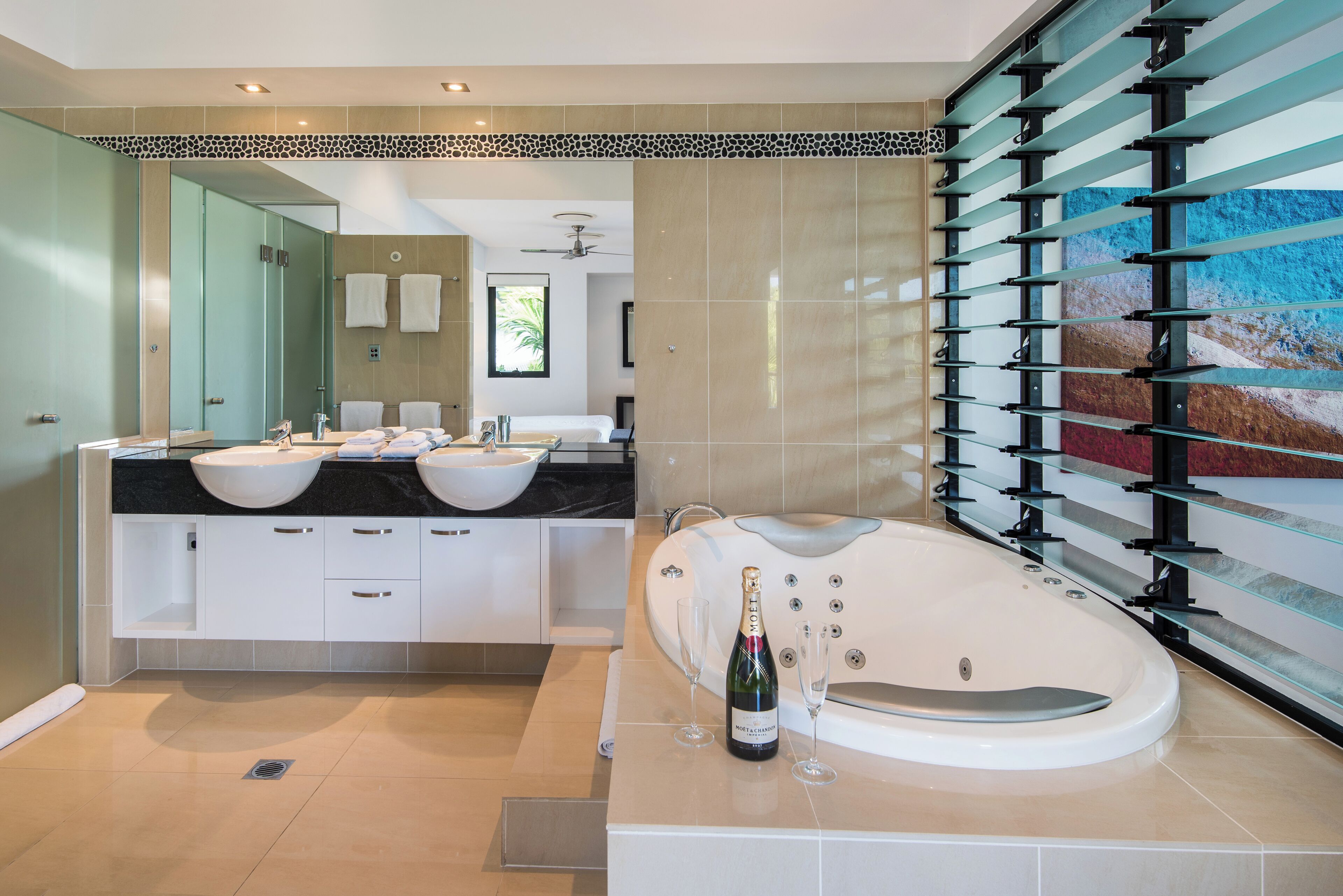 Ein modernes Badezimmer mit zwei Waschbecken, einer großen Badewanne und einer Duschkabine aus Glas.
