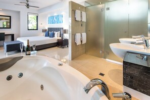 A modern hotel room with a large bathtub, a separate shower area, a bed with a view, and a well-lit bathroom with a large sink and mirror. - Edge Apartment 17, Edge Apartment 17 on Hamilton Island (Hamilton Island)