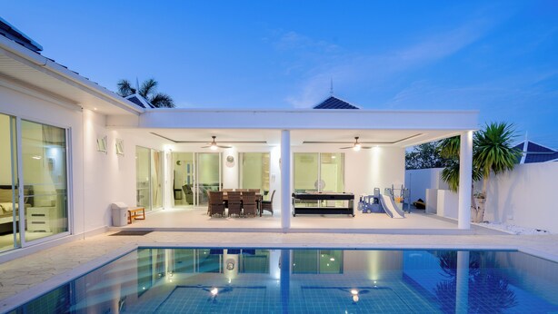 A modern house with a swimming pool, large windows, and a covered patio area.