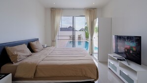 A modern hotel room with a large bed, a TV, and a view of a swimming pool.