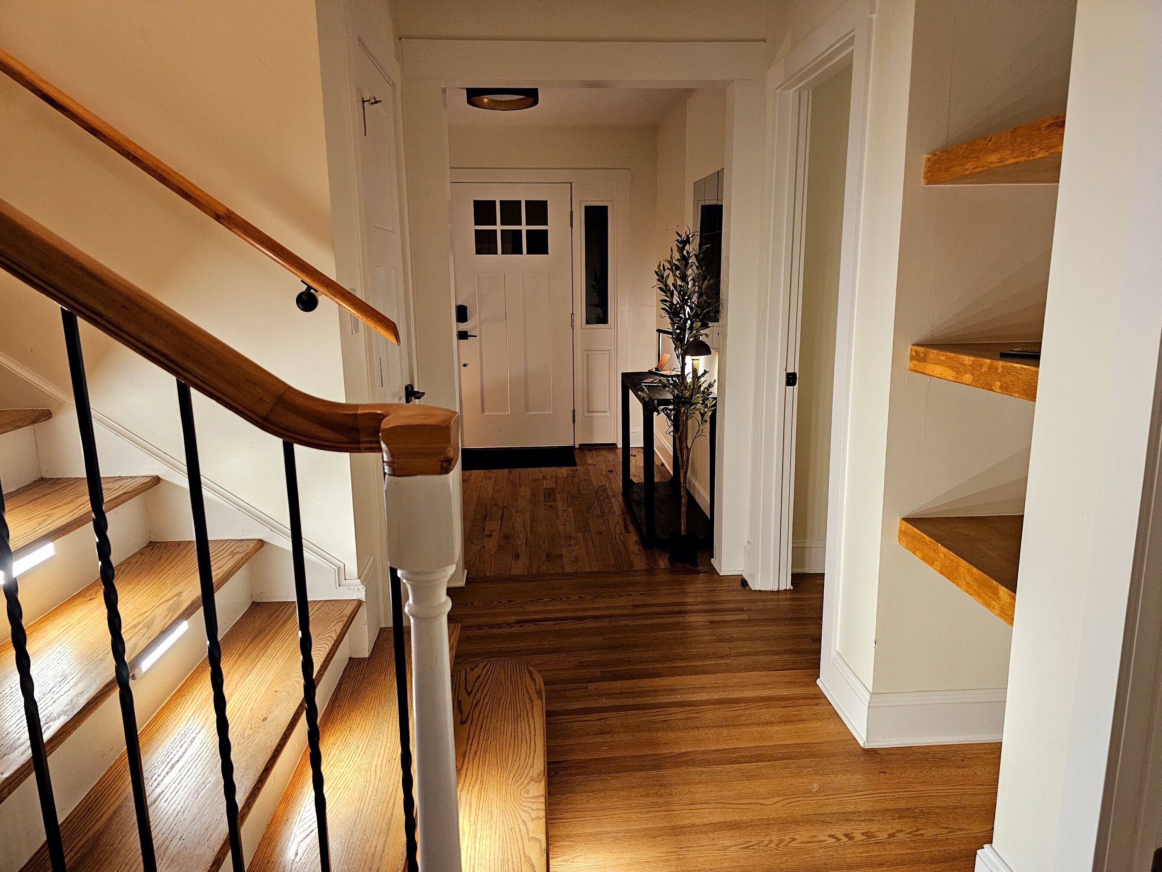 Un escalier en bois avec une rampe blanche menant à une porte.