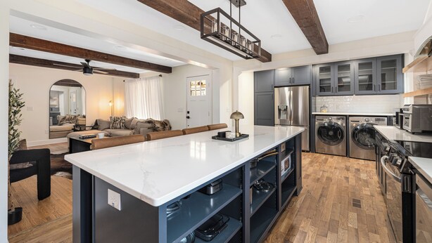 Een moderne keuken met inbouwapparatuur, een centraal eiland en zichtbare houten balken.