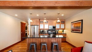 Una cocina moderna con armarios de madera, electrodomésticos de acero inoxidable y una isla central con taburetes.