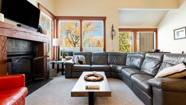 Una sala de estar con chimenea, un sofá modular, una mesa de centro y un televisor.