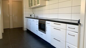 A modern kitchen with white cabinets, black countertops, and a stainless steel range hood. - Great Bungalow Near the Beach and sea (Sint Maartensvlotbrug)