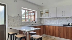 Una cocina moderna con una isla grande, armarios de madera y tres taburetes de bar.