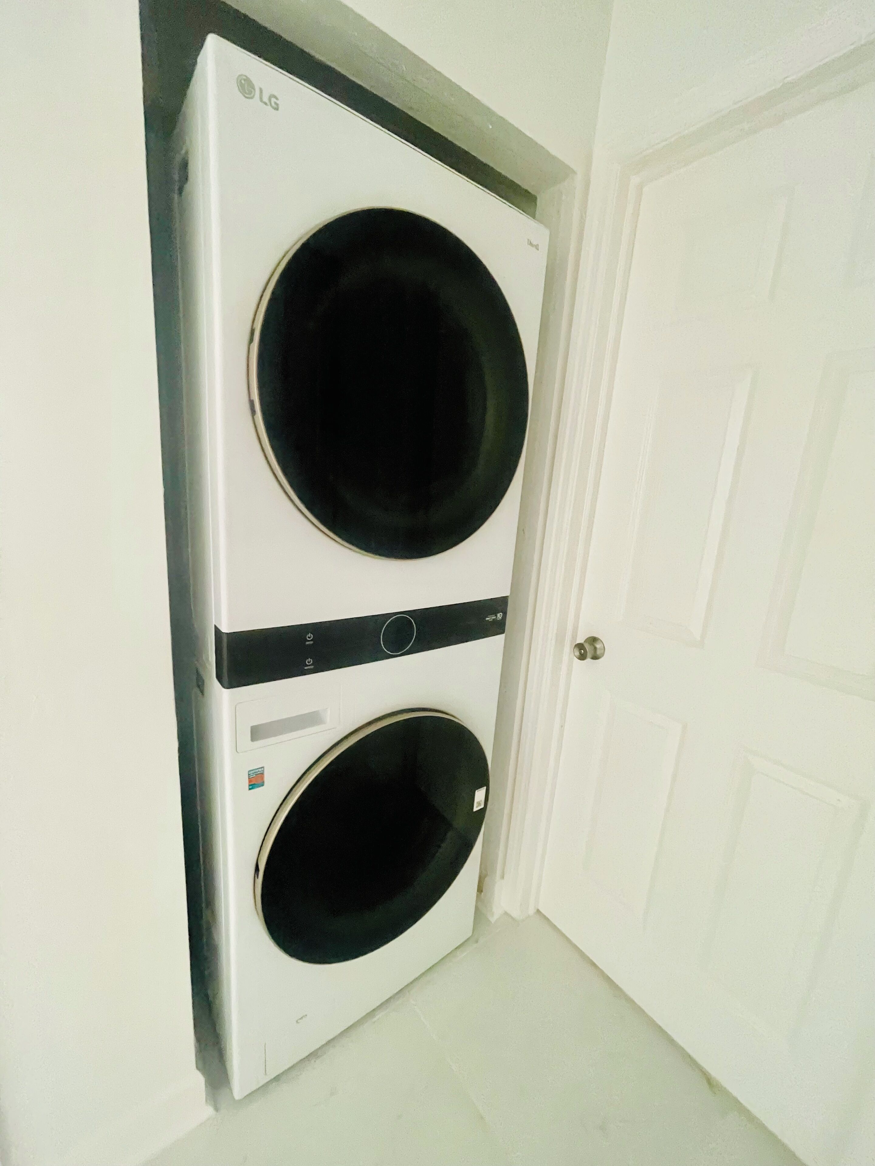 A wall-mounted LG washer and dryer unit in a room with a white door.