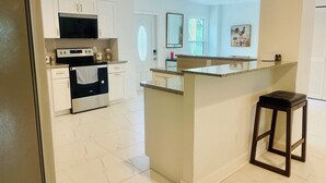 Eine moderne Küche mit weißen Schränken, einem eingebauten Backofen und einer Arbeitsplatte aus Granit.