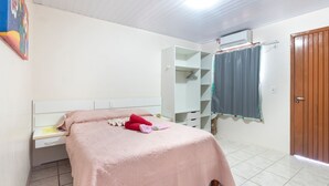 Une chambre à coucher comprenant un lit, un bureau, une armoire et une fenêtre avec des rideaux.