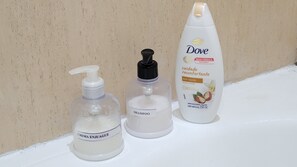 Drei Flaschen Dove Shampoo auf einer weißen Oberfläche vor einer beige gefärbten Wand.