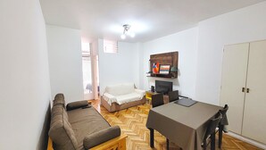 A small living room with a sofa, a table, a TV, and a wardrobe. - Luminoso, muy Completo y Bien Ubicado (Buenos Aires)