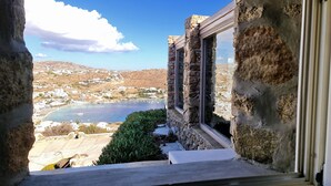A stone building with a view of a coastal landscape, including a body of water and distant hills. - Villa Tavani Agios Ioannis Mykonos (Mykonos)