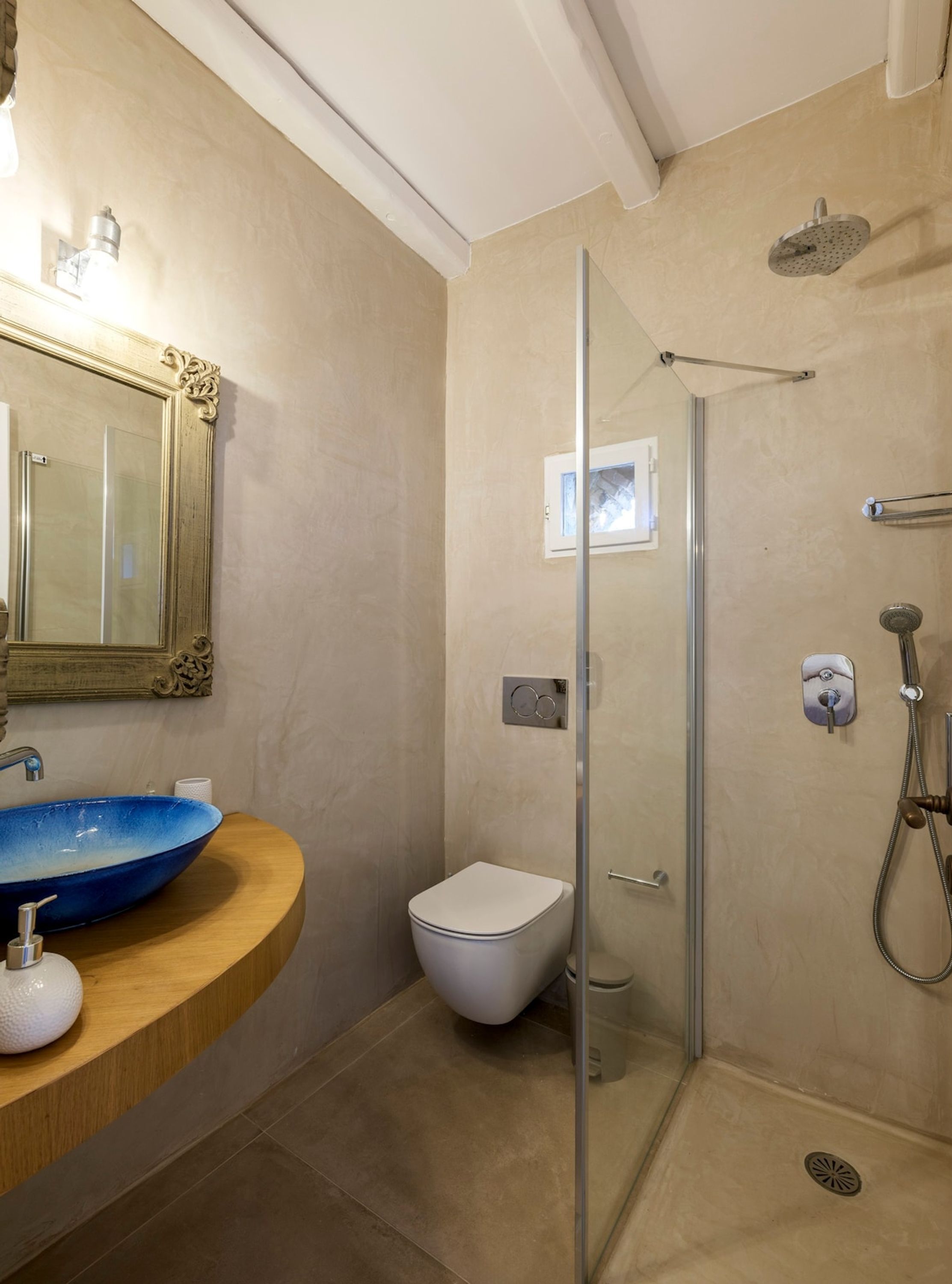 Une salle de bain avec une douche à parois de verre, des toilettes blanches et un lavabo bleu.