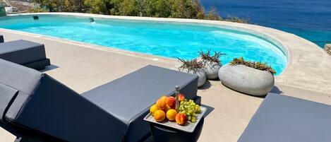 A poolside area with lounge chairs and a fruit tray.