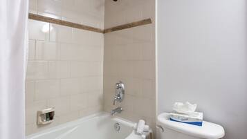 A bathroom with a bathtub, a showerhead, a toilet, and a towel rack.