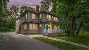 Ett tvåvåningshus med en veranda på framsidan, en skorsten och ett garage.