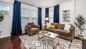 A living room with a brown sofa, two armchairs, a coffee table, and a patterned rug. - Pet-friendly Furnished Apt Near Emu Free Parking 2 Bedroom Apts (Ypsilanti)