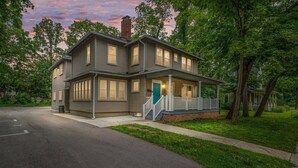 A two-story house with a front porch, a chimney, and a garage. - Pet-friendly Furnished Apt Near Emu Free Parking 2 Bedroom Apts (Ypsilanti)