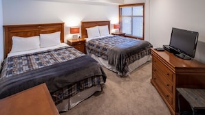 A hotel room with two beds, a TV, a dresser, and a window with blinds. - 3419b - Double Queen Standard Powderhorn Lodge Suite (Salt Lake City)