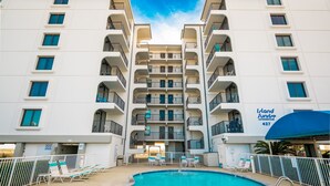 A multi-story hotel with a swimming pool, balconies, and a sign indicating 'Island Sunrise Condominiums 427'. - Island Sunrise 663 2 Bedroom Condo (Gulf Shores)