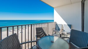 A balcony with a view of the beach and ocean. There are chairs and a table on the balcony. - Island Sunrise 663 2 Bedroom Condo (Gulf Shores)