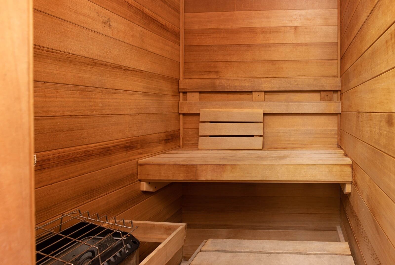 Un sauna avec des murs en bois et un banc.