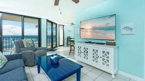 A spacious living area with a large TV, comfortable seating, and a view of the ocean. - Phoenix Iii 3063 1 Bedroom Condo (Orange Beach)