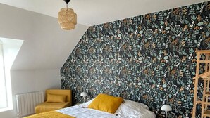 Ein Schlafzimmer mit einem Bett, einem Holztisch, einem Stuhl, einem kleinen Tisch mit einer Lampe und einer Heizung.