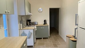 Eine kleine Küche mit Holzbalken, einem Spülbecken, Schränken, einem Toaster und einem Kühlschrank.