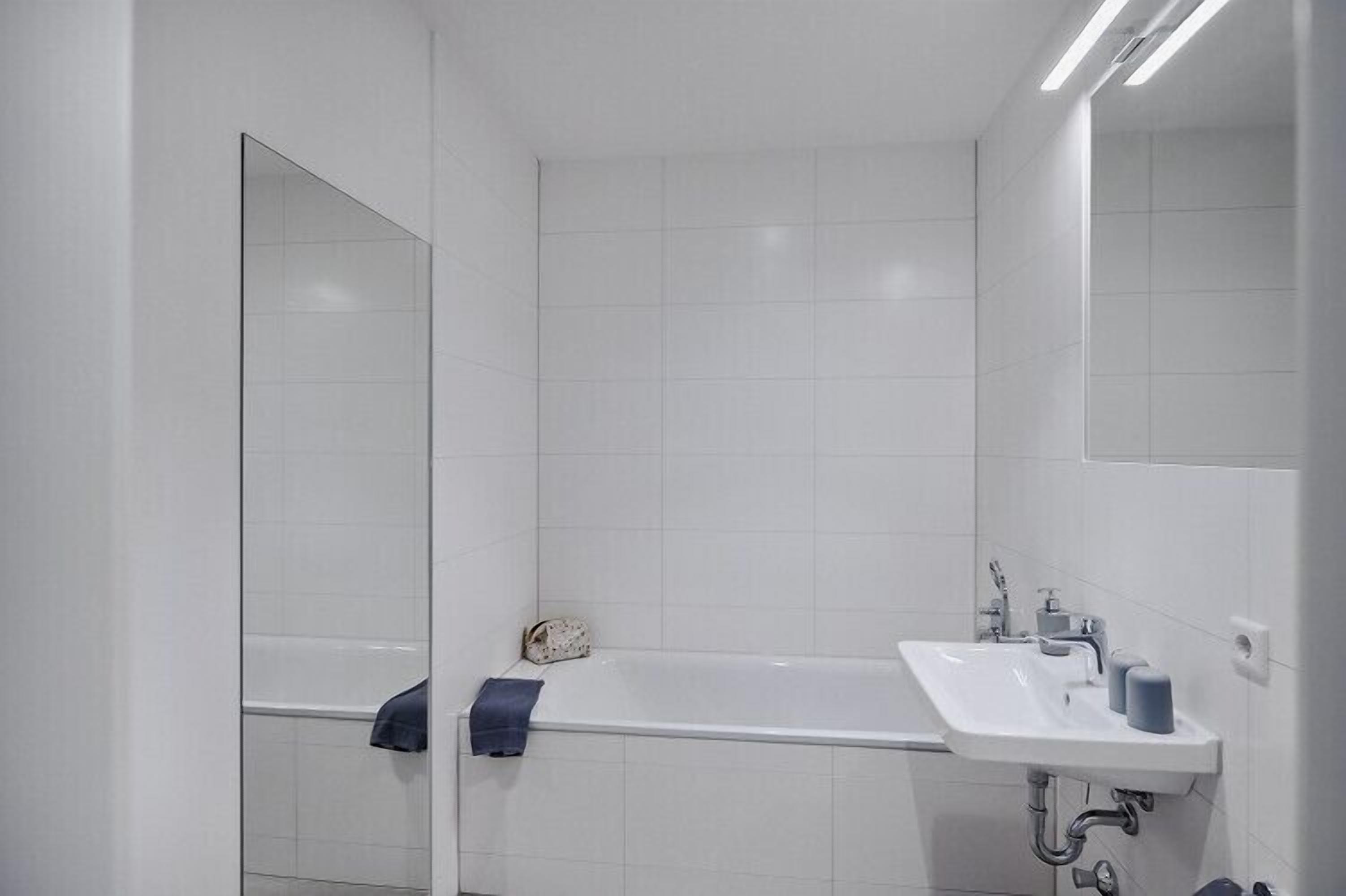 Une salle de bain moderne avec une baignoire, un lavabo et un miroir.