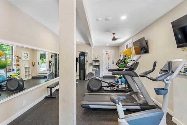 A gym with treadmills, stationary bikes, and exercise balls.