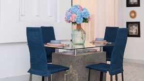 A dining area with a round table, two blue chairs, and a vase of flowers. - Les Jardins de René Villa (Yaoundé)