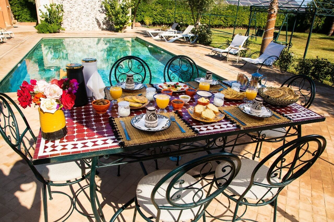 A dining table set outdoors with a pool in the background.