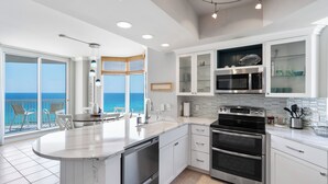 A modern kitchen with a large island, built-in ovens, and a view of the ocean.