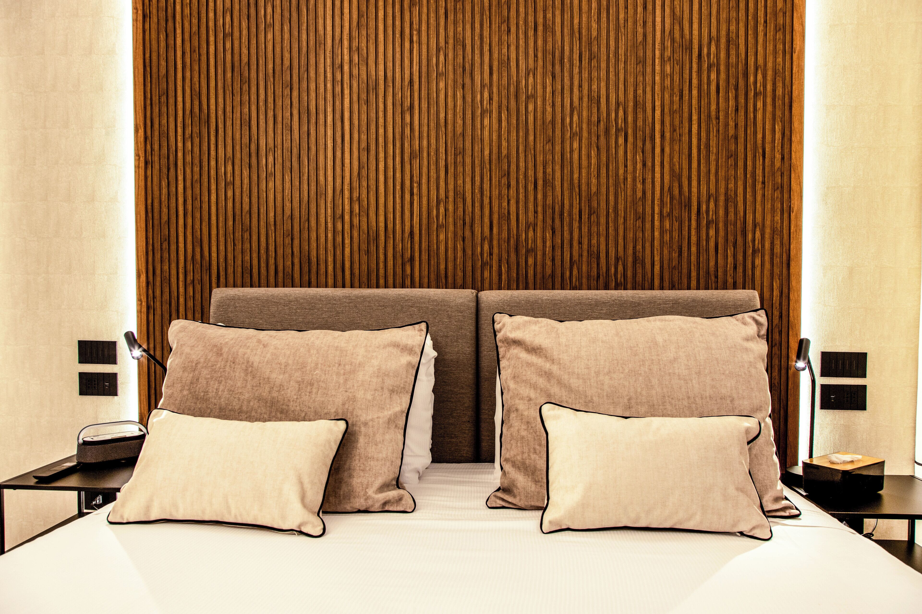 Una habitación de hotel con una cama grande, dos mesitas de noche y un panel de pared de madera.