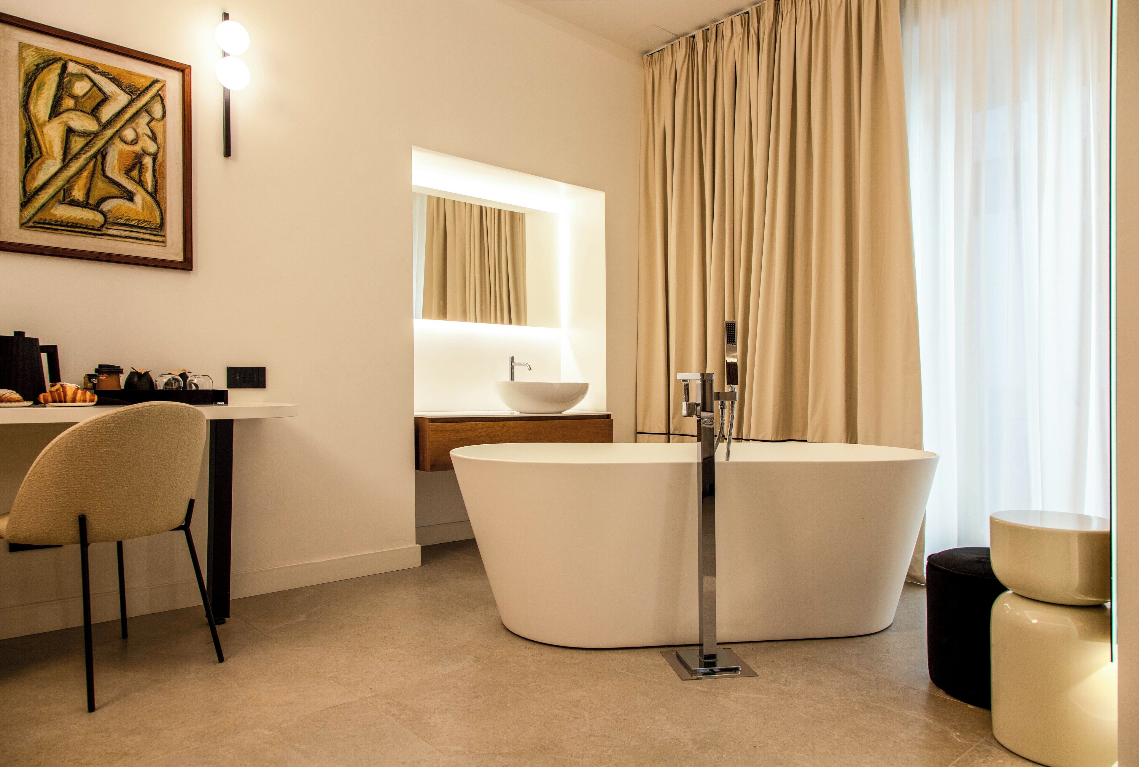 Ein modernes Badezimmer mit einer freistehenden Badewanne, einem Waschtisch mit Spiegel und einem Sessel.