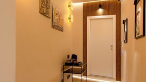 A hallway with a wooden bench, framed artwork, and a door at the end. - Mamalu - Corso Umberto (Naples)