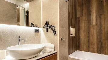 A modern bathroom with a large white vessel sink, a wooden vanity, a glass shower enclosure, and a wooden wall panel.