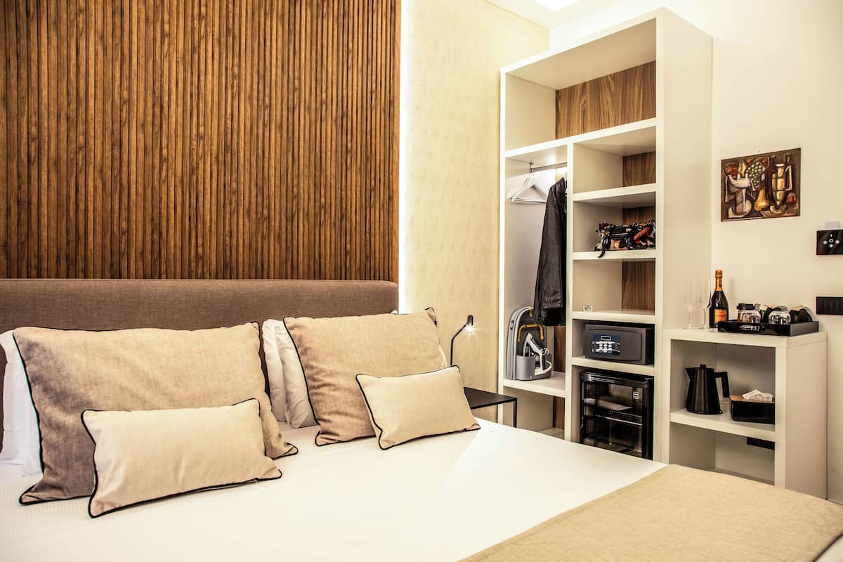 Une chambre d’hôtel avec un lit, une armoire et une petite table sur laquelle se trouvent une bouteille et des verres.