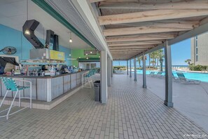 A covered outdoor area with a pool, bar, and seating.